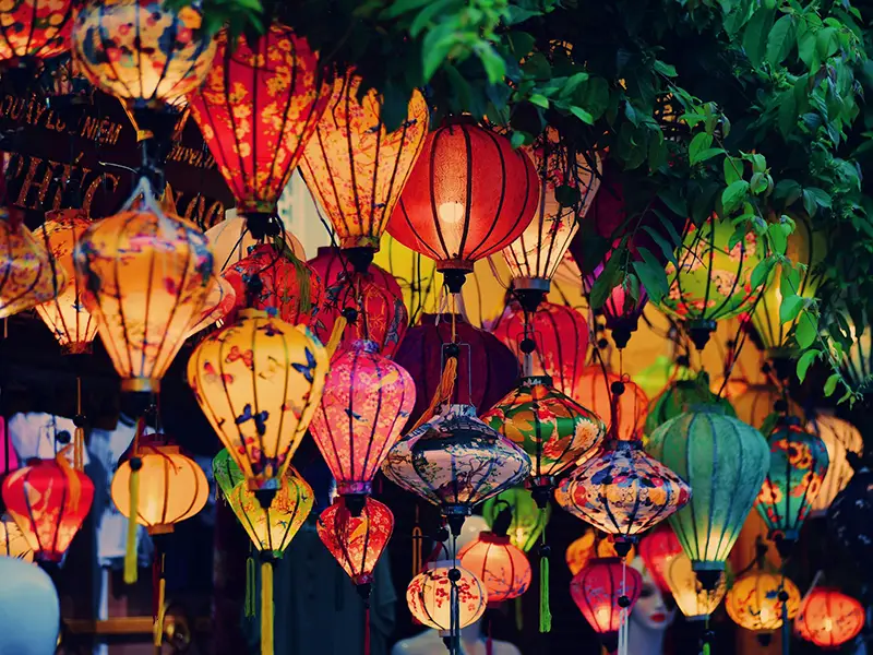 Colorful silk lanterns glowing at night, hanging above a street in Hoi An.