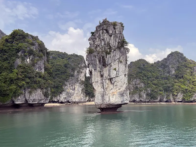 Limestone rock emerging from still water in Lan Ha Bay
