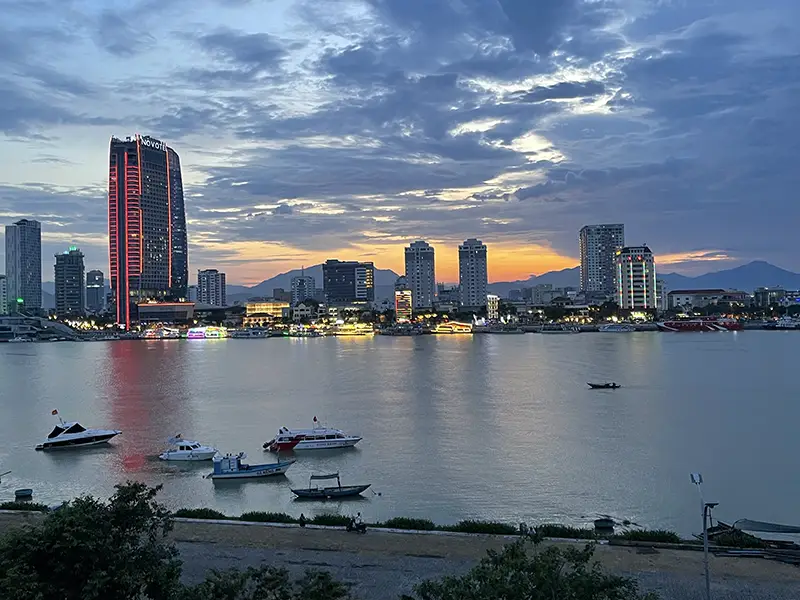 Evening skyline in Da Nang with modern skyscrapers reflecting in the river.