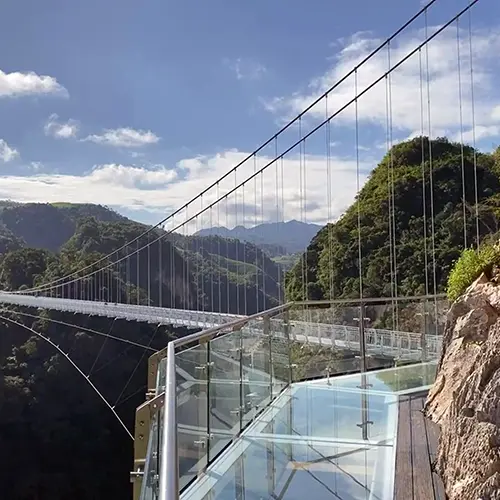 Side view of Bach Long Glass Bridge in Moc Chau, Vietnam, with glass panels and surrounding forested mountains