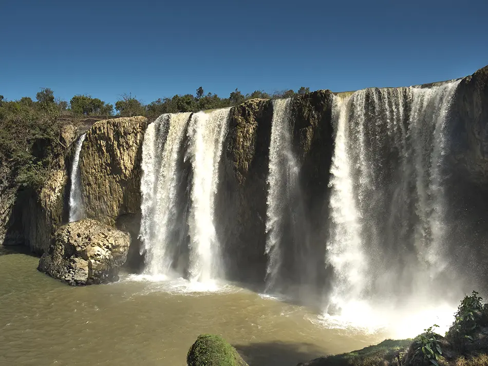 Bao Dai Waterfall flowing down a rocky slope surrounded by forest near Da Lat, named after Vietnam’s last emperor