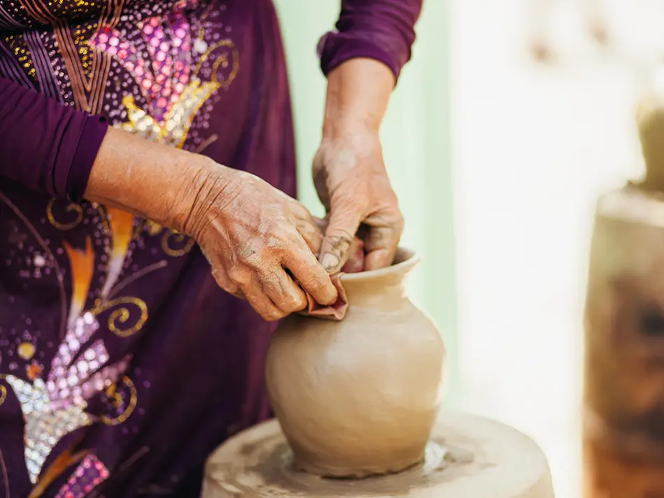 Vietnamese artisan shaping clay pot by hand, preserving traditional skills in off the beaten path Bat Trang
