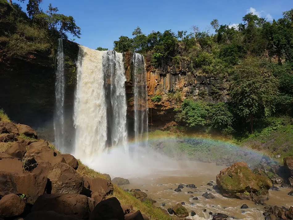 Phu Cuong Waterfall crashing down basalt cliffs with a rainbow in Kon Tum, Central Vietnam