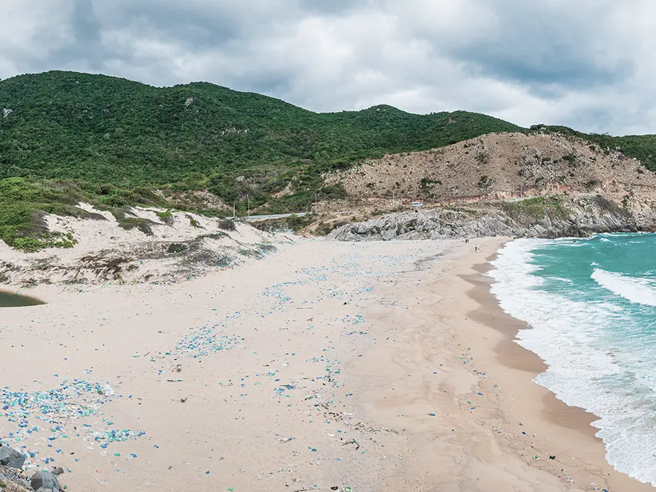 Plastic debris on a secluded Vietnam beach, highlighting the impact of tourism on hidden coastal areas