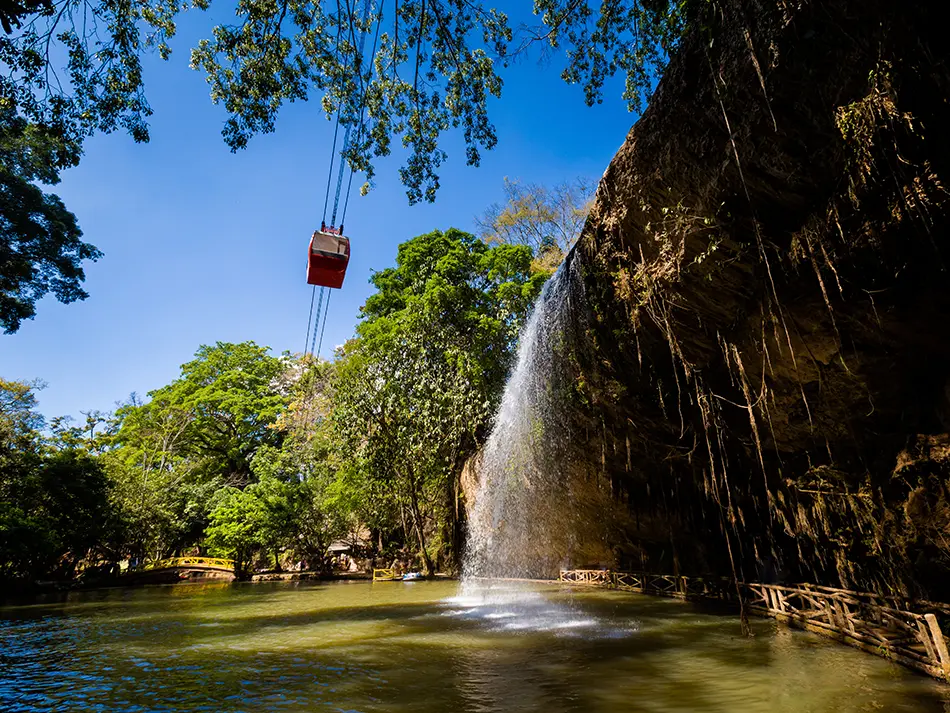 Prenn Waterfall in Da Lat with a cable car overhead, surrounded by forest and visitor walkways