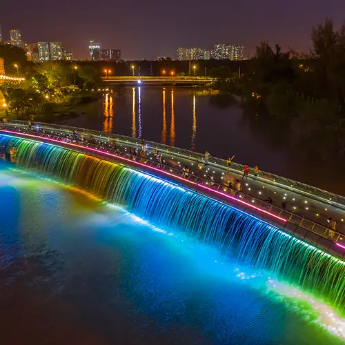 Panoramic cityscape view of Ho Chi Minh City with the glowing Starlight Bridge over Crescent Lake at dusk