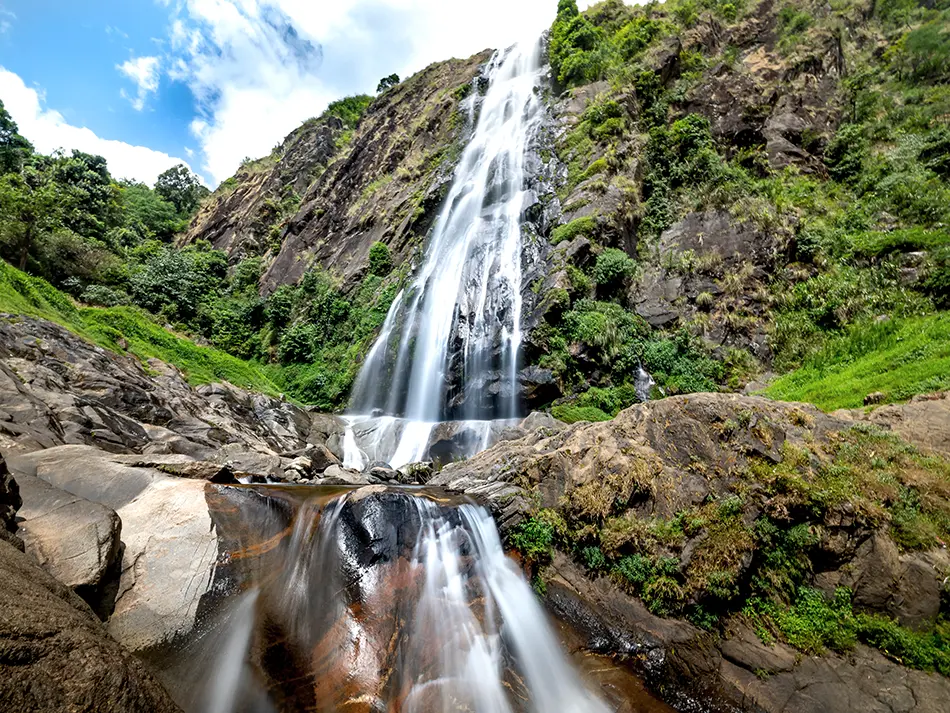 Tac Tinh Waterfall plunging down a rocky cliff surrounded by forest in Northern Vietnam