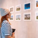 Visitor viewing framed artwork in a modern exhibition space, representing the experience at the best art galleries in Vietnam.