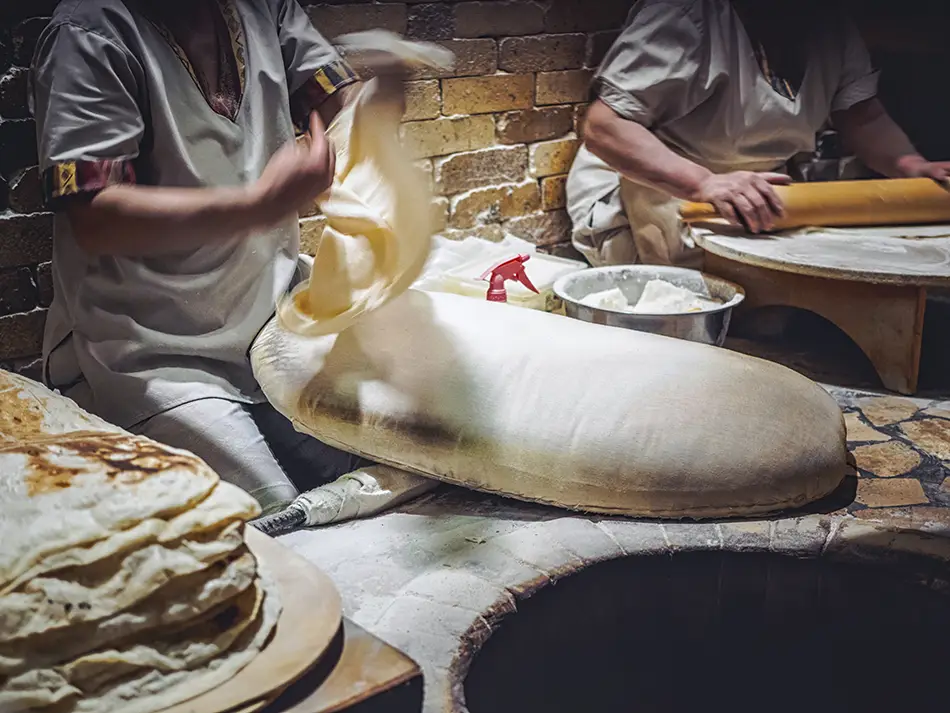 Traditional Armenian lavash bread being made in a clay tonir oven during a culinary workshop