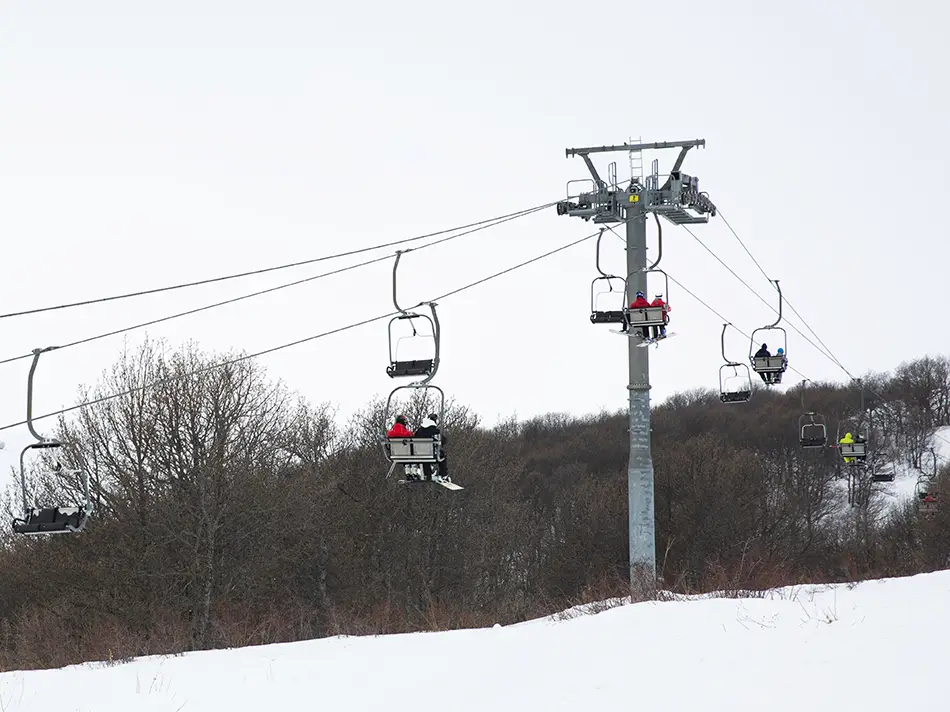 People riding a ski lift over snowy slopes in Armenia