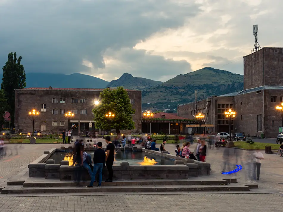  Locals relaxing at Goris town square with mountains in the background, a scenic Armenian getaway