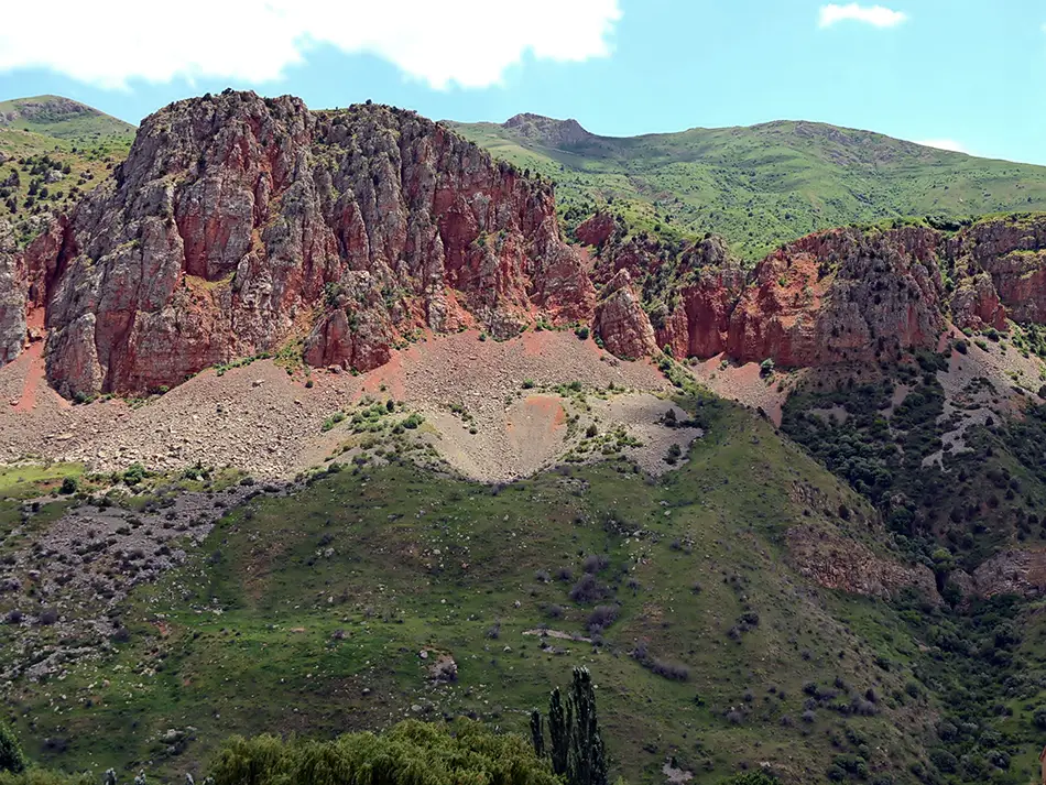 Red cliffs and green slopes of Amaghu Gorge near Areni in Armenia on a sunny day.