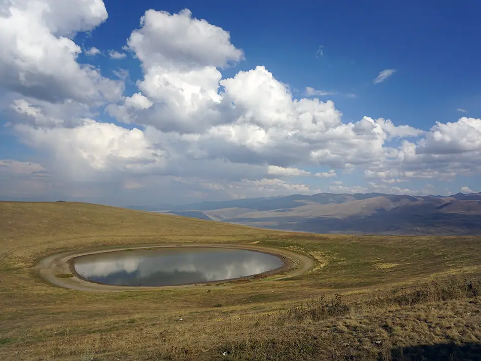 Crater lake on Mount Armaghan under summer clouds, suggesting the best time to visit Sevan.