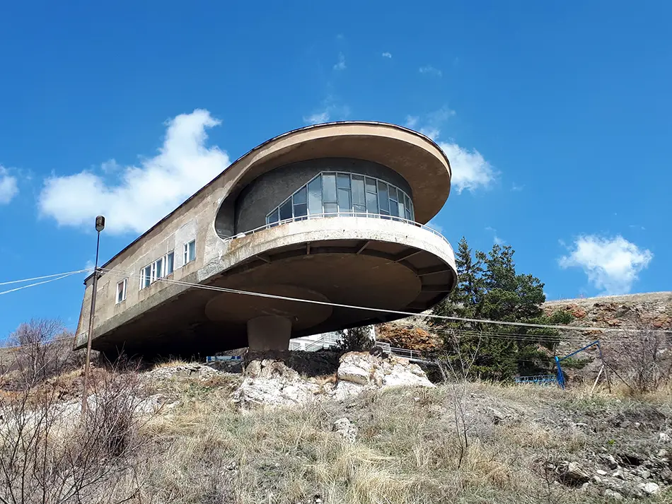 Futuristic Writers' House of Sevan with curved concrete facade against a bright sky.