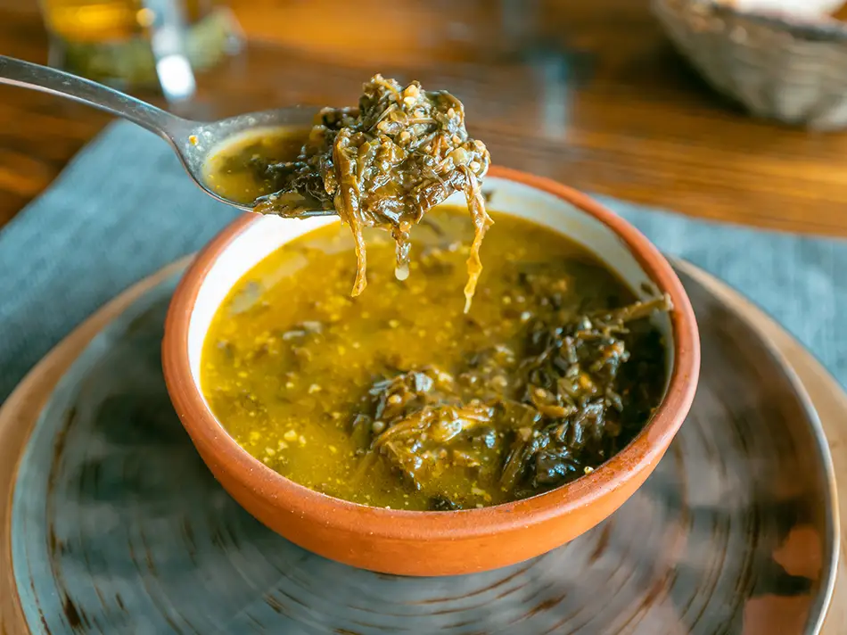 A bowl of traditional Armenian aveluk soup made with sorrel leaves, a staple of local Armenian food.