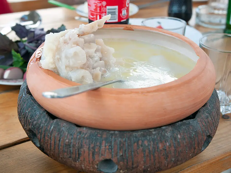 Traditional Armenian khash soup served hot in a clay bowl, known for its ceremonial importance.