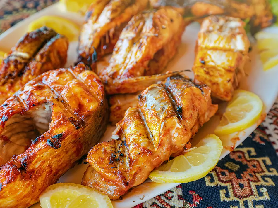 Grilled trout (ishkhan) from Lake Sevan with herbs, one of the best food to try in Armenia for seafood lovers.