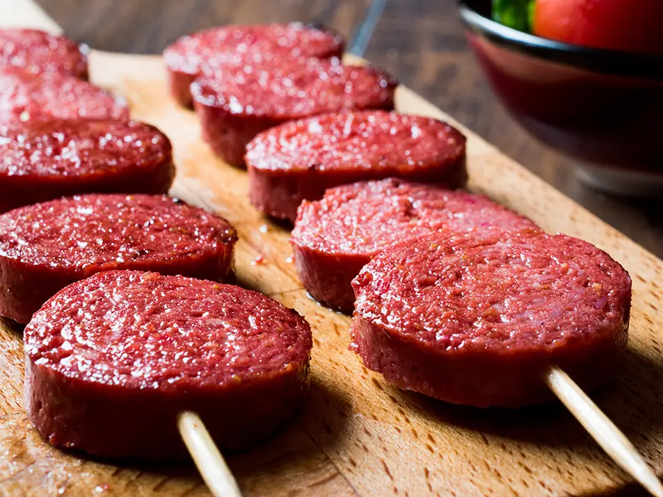Armenian sujuk sausage laid out on a wooden board, showing traditional meat preparation methods.
