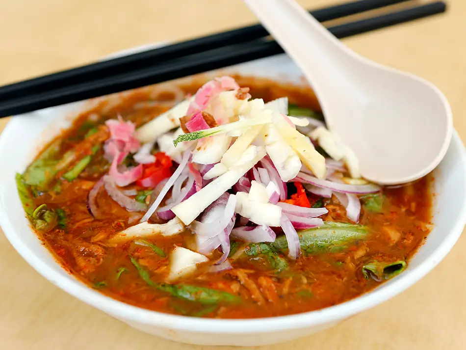 Tangy asam laksa topped with pineapple, mint and cucumber, a highlight of best dishes in Malaysia.