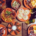 Best food in Georgia: overhead flat lay of khinkali, adjaruli khachapuri, mtsvadi and pkhali, plus others.