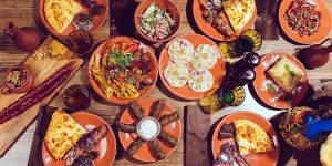Best food in Georgia: overhead flat lay of khinkali, adjaruli khachapuri, mtsvadi and pkhali, plus others.