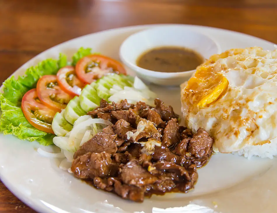 Lok Lak, classic Cambodian beef stir-fry, served with fresh vegetables—essential for any best food in Cambodia list