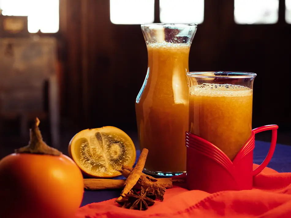 Typical Ecuador drinks canelazo, hot cinnamon aguardiente poured into glass mugs.