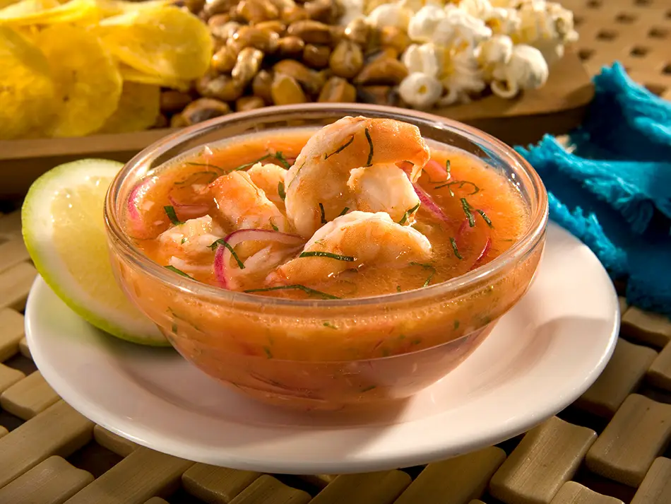 Shrimp ceviche in tomato-lime marinade, part of the Best food in Ecuador, topped with red onion and cilantro.
