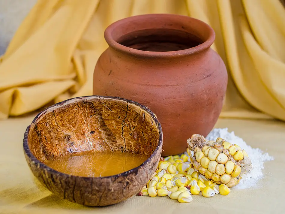 Fermented corn chicha de jora in a clay cup in Cusco, local beverage in Peru.