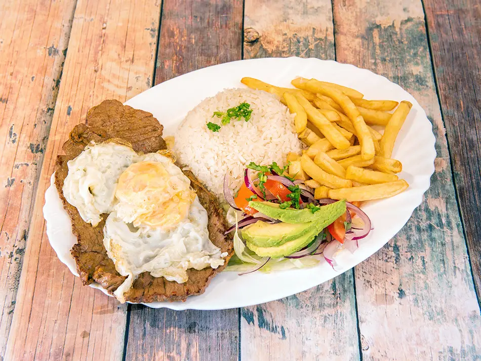 Thin steak with fries, rice, fried egg, avocado, and salad — on of the best dishes in Ecuador.