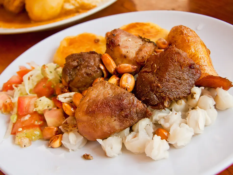 Crispy fritada pork with curtido, plantains, and mote, a street classic among typical Ecuador food.
