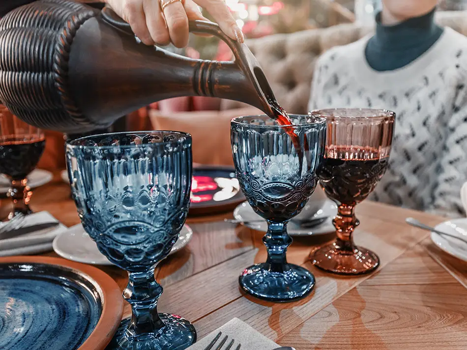 Qvevri wine tasting with glasses and clay jugs.