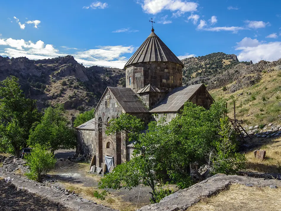 Gndevank Monastery above the canyon in Armenia, framed by rugged hills.