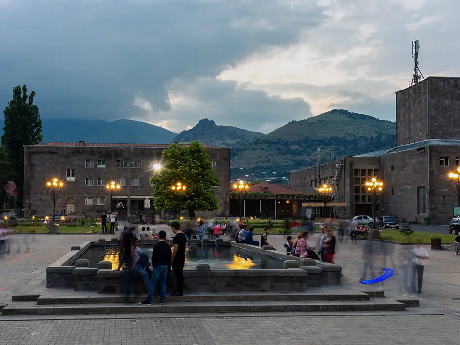 Nightlife in Goris begins on the central square, with evening lights and a fountain.