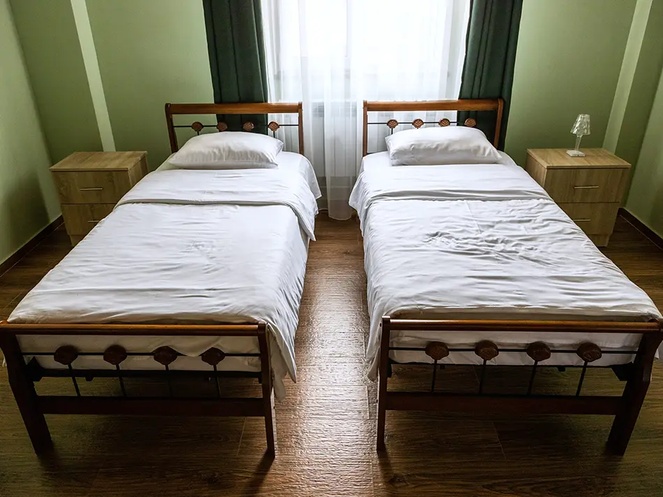 Simple twin room in a small hotel, neat bedding and wooden floor.