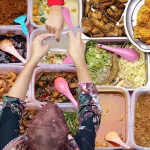 Overhead flat lay of Malaysia dishes: fried chicken, stir-fried noodles, spicy prawn curry