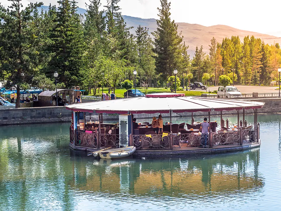 Calm lake with floating café and pines, illustrating why visit Jermuk.