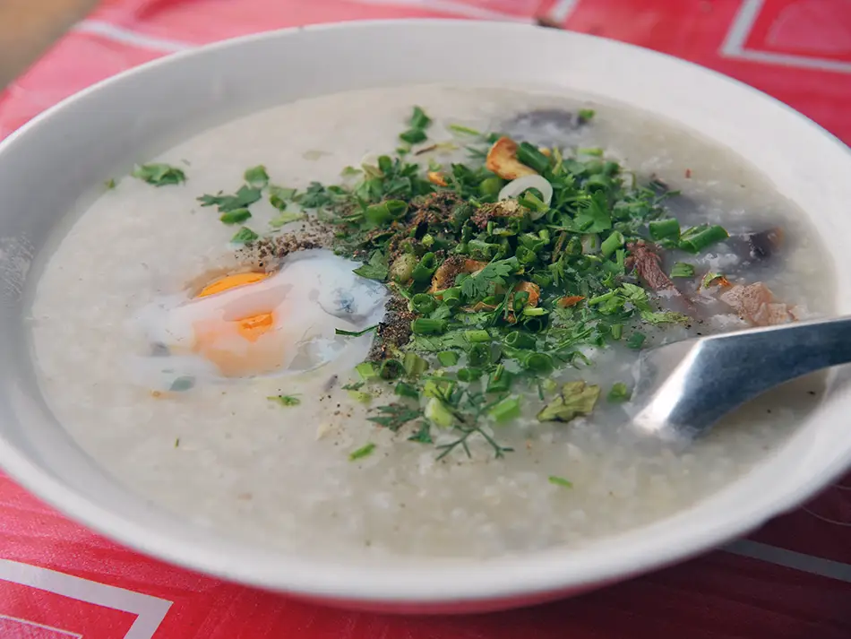 Comforting khao piak khao rice porridge with chicken, fried garlic and scallions — typical Lao food.