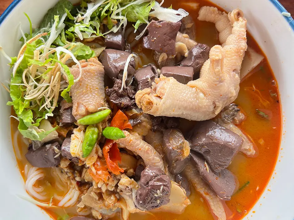 Vermicelli in coconut curry with shredded chicken and herbs — best food in Laos favorite.