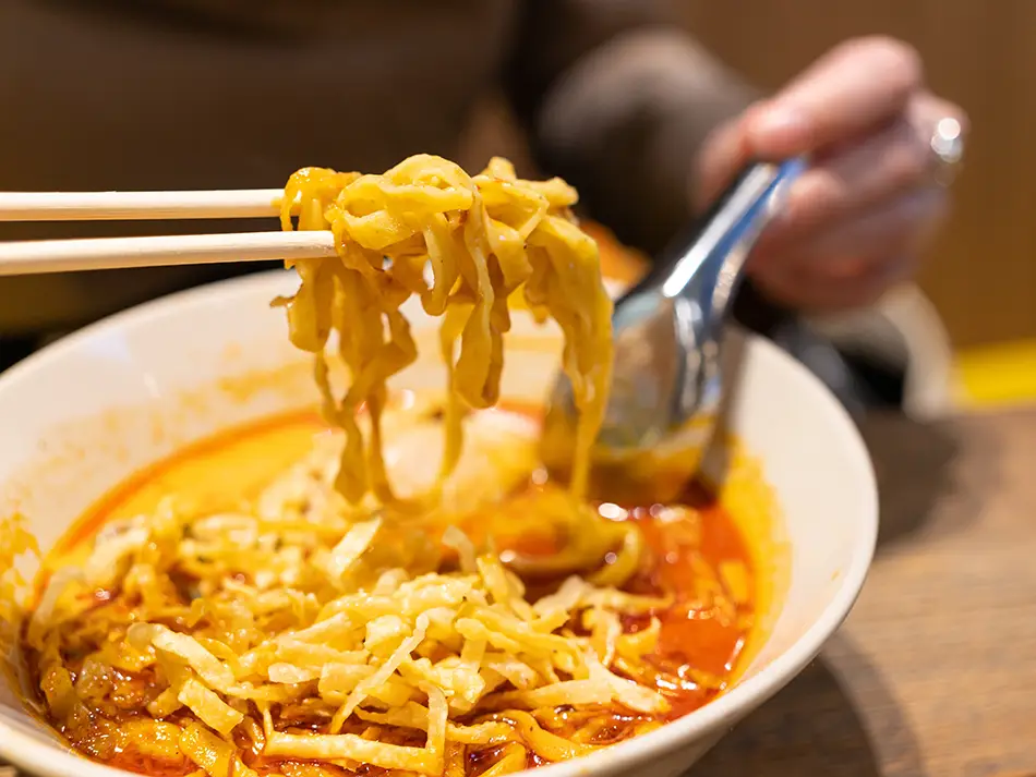 Luang Prabang khao soi with pork–tomato topping over wide noodles, richly aromatic — best food in Laos.
