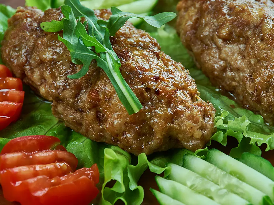 "Armenian kiufta meat patties served with fresh tomatoes and cucumbers, a grilled kofta-style dish