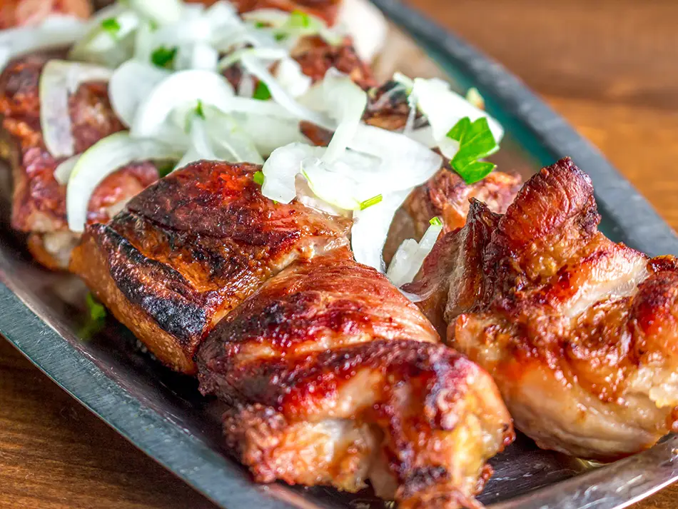 Mtsvadi charred pork skewers on a board in Kakheti.