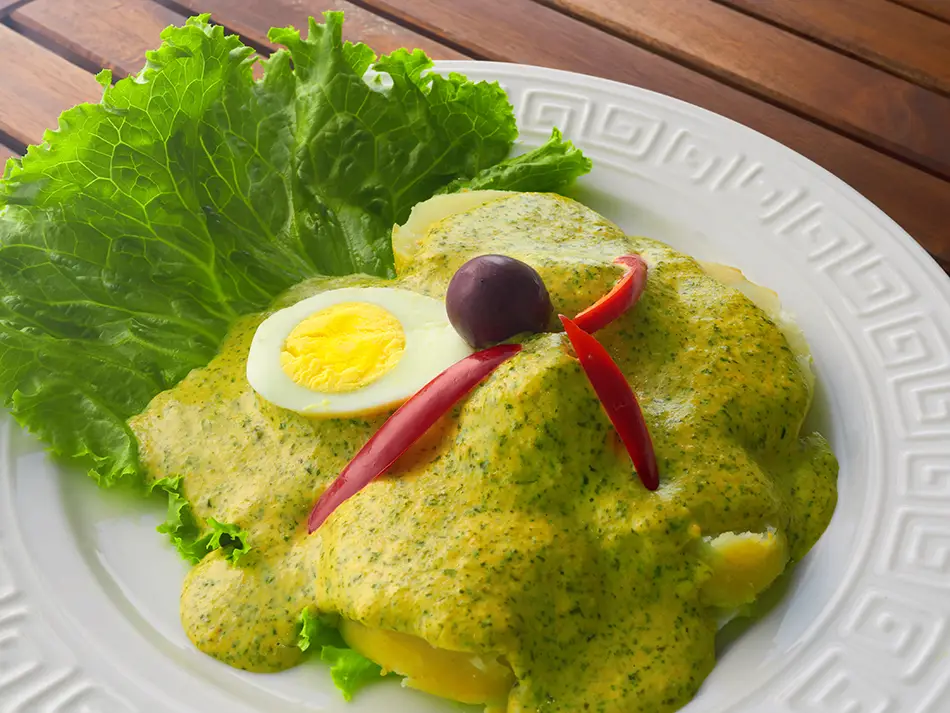 Boiled potatoes under huacatay-peanut sauce in Arequipa — famous Peru foods.