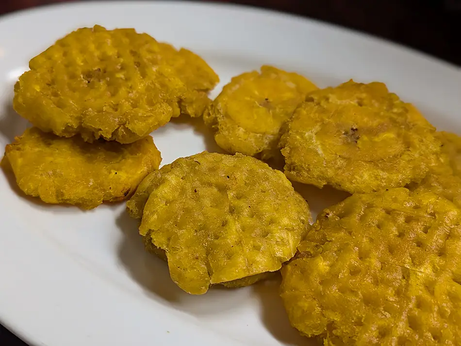 Typical Ecuador food includes crisp patacones arranged on a white plate.