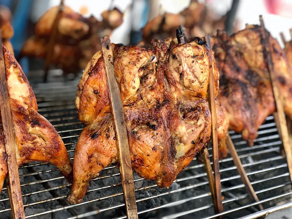 Charcoal-grilled ping gai chicken with crisp skin and dipping sauce, local food in Laos.