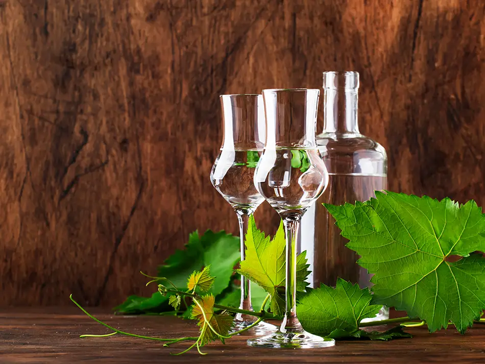 Pisco bottle and tasting glass at an Ica bodega, label and grapes visible.