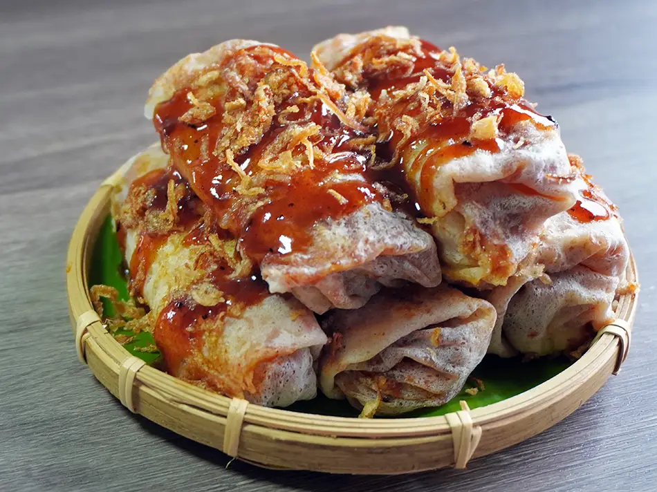 Fresh popiah basah filled with vegetables and peanuts, typical Malaysian food option.