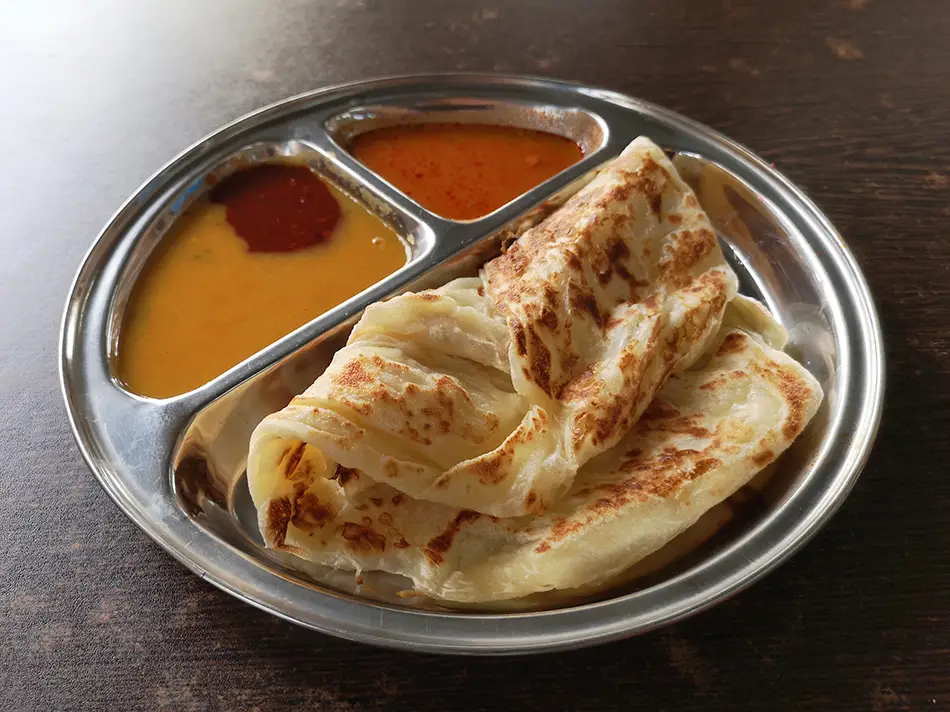 Flaky roti canai served with dhal curry, a beloved traditional Malaysian dish.