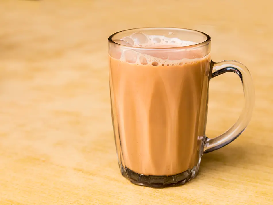 Frothy teh tarik being poured from a height, showing traditional Malaysian  beverage culture.