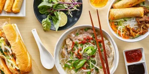 Best food in Vietnam shown in an overhead flat lay of bánh mì, bánh xèo, bún chả, cá kho tộ and more.